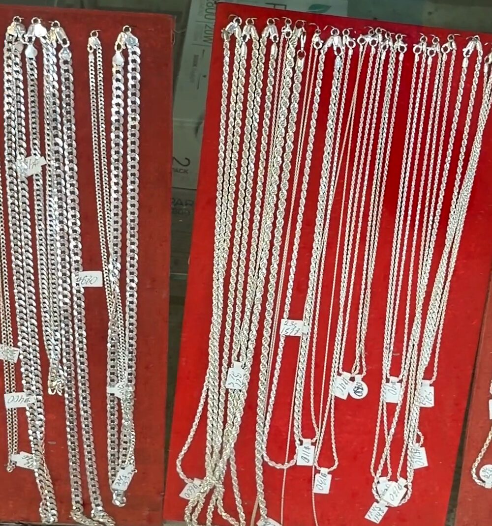 Muchas cadenas plateadas de distintos grosores colgando en dos tableros de terciopelo rojo.