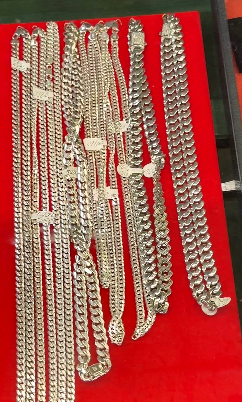 Cadenas plateadas de eslabón grueso colgando sobre terciopelo rojo.