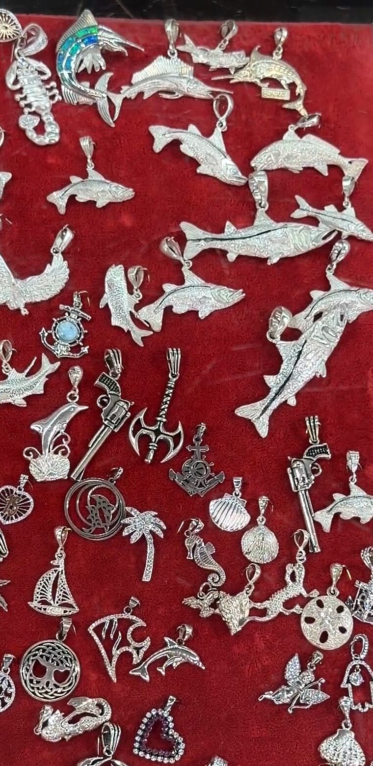 Delfines, peces, un escorpión, palmeras y veleros plateados sobre terciopelo rojo.